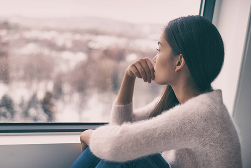 Young woman looking out of the window looking concerned